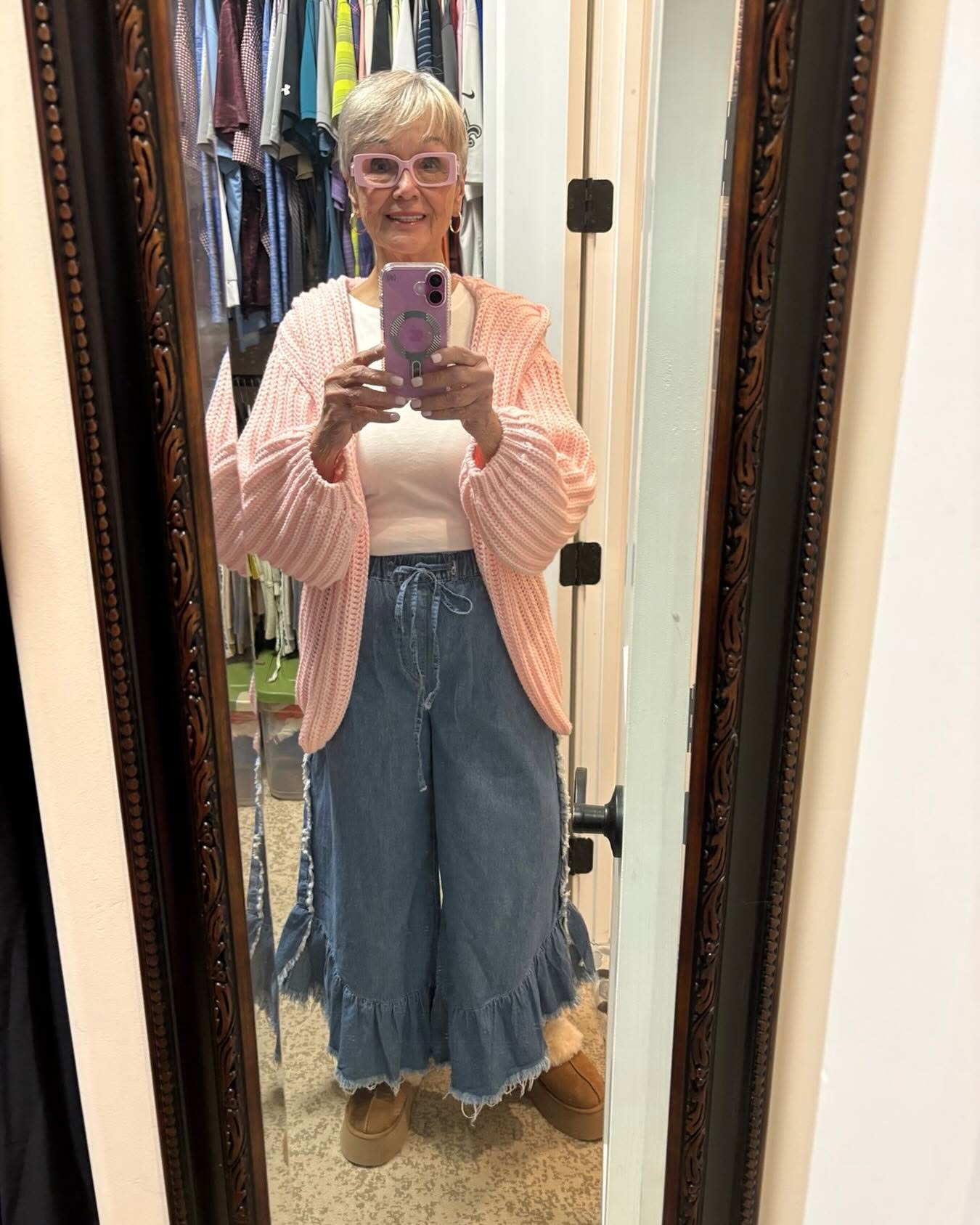 Mindy in a pink cardigan and ruffled wide-leg jeans, mirror selfie
